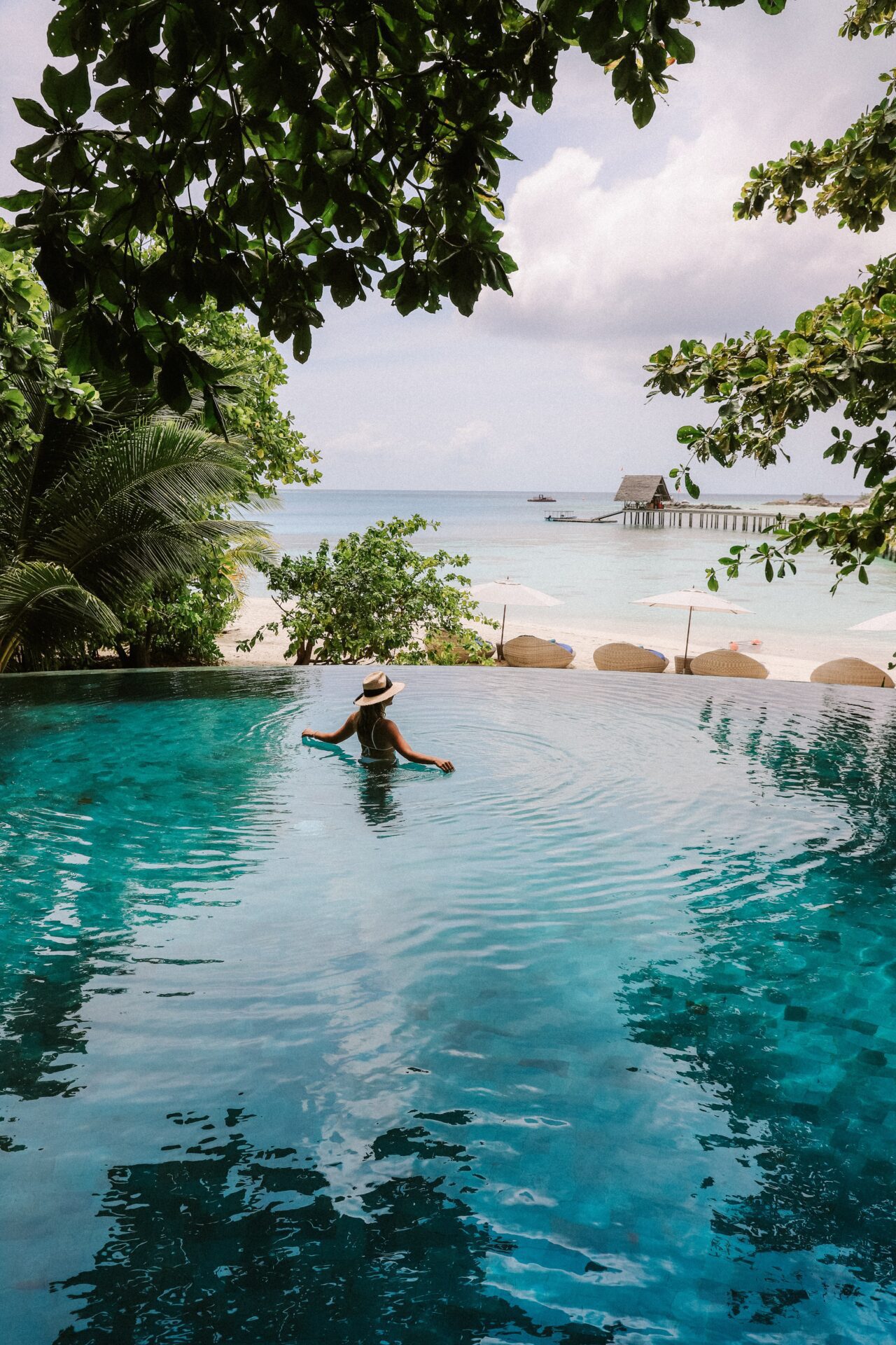 chelsea-gates-0653_wY0nRc-unsplash-1-scaled-1 Person stands in infinity pool looking out at a tropical beach